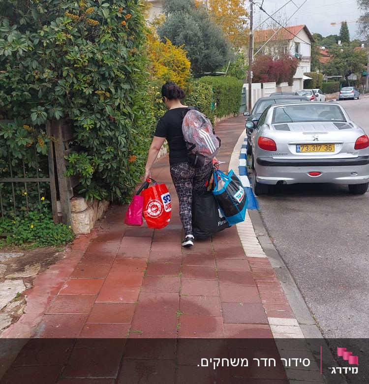 אישה נושאת שקיות קניות צבעוניות על מדרכה